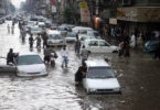 Pakistani commuters travel on a flooded street following a heavy rainfall in Karachi. via Shutterstock