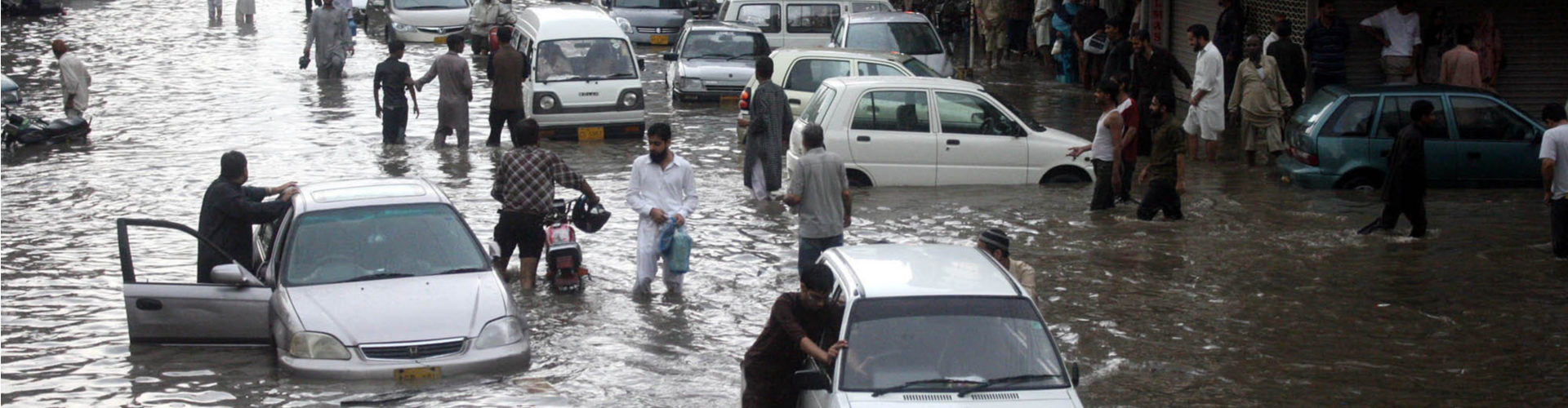 Pakistani commuters travel on a flooded street following a heavy rainfall in Karachi. via Shutterstock