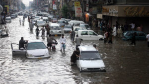 Pakistani commuters travel on a flooded street following a heavy rainfall in Karachi. via Shutterstock