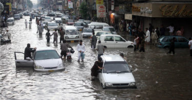 Pakistani commuters travel on a flooded street following a heavy rainfall in Karachi. via Shutterstock